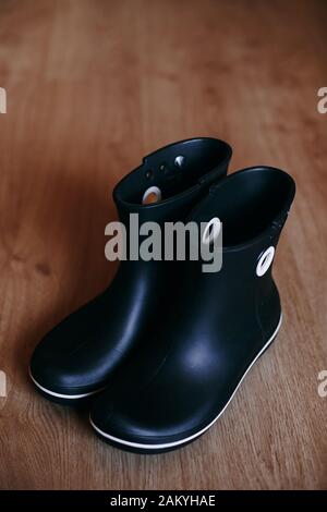 Black rubber boots isolated on wooden background. Stock Photo