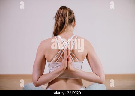 Young sporty attractive woman practicing yoga, meditating in yoga pose, working out, wearing sportswear, indoor full length, light yoga Studio Stock Photo