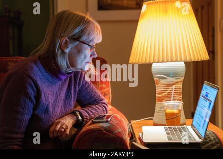 Woman reading at home on a laptop computer Stock Photo