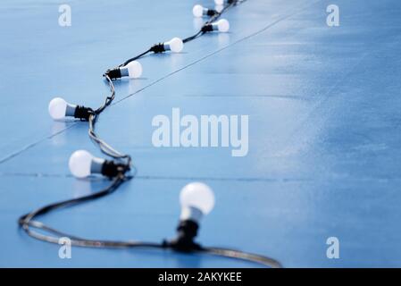 Abstract blue background with a garland of light bulbs on a wire Stock Photo