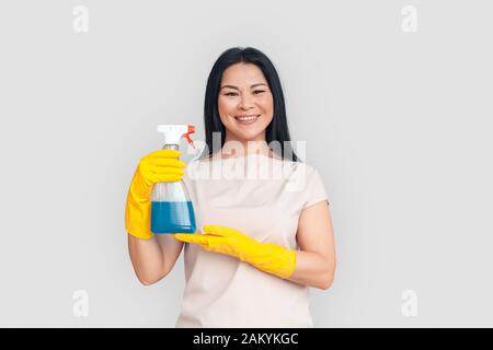Freestyle. Asian woman in gloves standing isolated on white posing with spray smiling cheerful Stock Photo