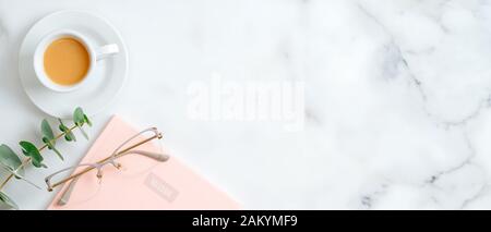 Pink paper notepad, women's glasses, cup of coffee, eucalyptus leaf on marble background with copy space. Beauty blog banner mockup Stock Photo