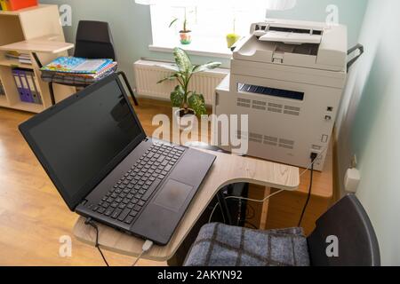 Open black laptop computer on a small chair table in office interior. Stock Photo