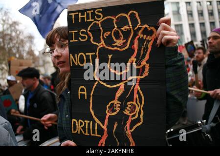 Protester holds a placard during a demonstration by members of the climate change activist movement Extinction Rebellion (XR) against Australian government's response to its ongoing bush fires outside the Australian High Commission in London.Wildfires have burned more than 12 million acres of Australian land since September last year, with the states of New South Wales and Victoria most severely affected and with the fire season still far from over. Australian Prime Minister Scott Morrison is facing intense criticism over his handling of the crisis, including his decision to go on holiday to H Stock Photo