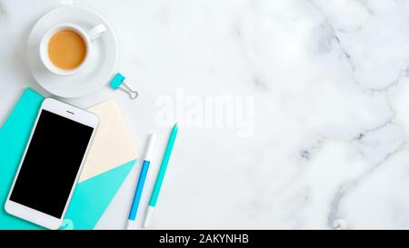 Flat lay feminine home office desk with smartphone empty screen mockup, mint notebook, stationery, stylish accessories, coffee cup on marble backgroun Stock Photo