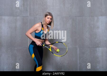 Beautiful girl tennis player with a racket isolated on grey background. Strong woman concept. Stock Photo