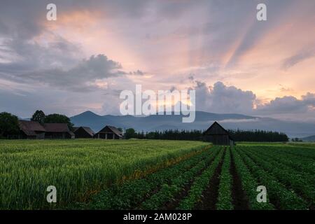 Clearing storm over a rural landscape with traditional barns in Turiec region, central Slovakia. Stock Photo