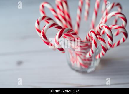 Close up of a cup full of candy canes on white weathered wood table. Stock Photo