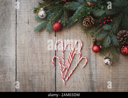 Candy canes on weathered wood table with christmas decor from above. Stock Photo