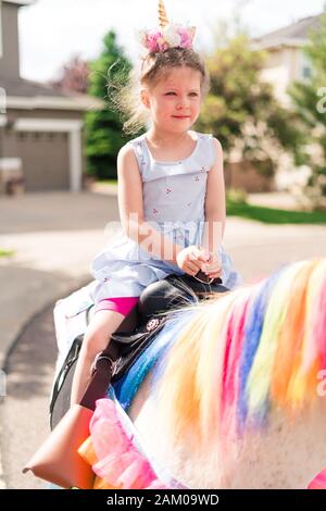 Little girl riding a unicorn at the little girl birthday party. Stock Photo