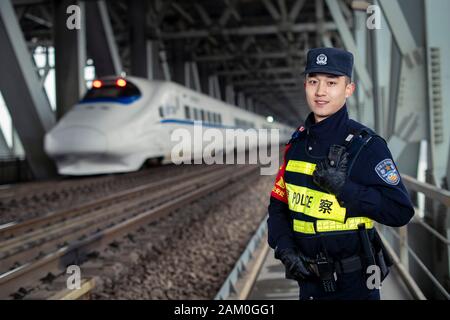 (200111) -- WUHAN, Jan. 11, 2020 (Xinhua) -- Zhou Chenyu, a railway policeman of Wuhan, poses for a photo on the Tianxingzhou bridge across the Yangtze River in Wuhan, central China's Hubei Province, Jan. 6, 2020. China, the world's most populated country, on Jan. 10 ushered in its largest annual migration, 15 days ahead of the Spring Festival, or the Lunar New Year. This year, three billion trips will be made during the travel rush from Jan. 10 to Feb. 18 for family reunions and travel, according to official forecast. The 40-day travel rush is known as Chunyun in Chinese. The Lunar New Yea Stock Photo