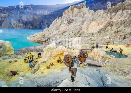 Sulphur miner hiking down into the crater of Kawah Ijen volcano in East Java, Indonesia. Stock Photo