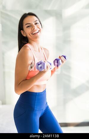 Young woman is exercising with dumbbells at home. Fitness, workout, healthy living and diet concept. Stock Photo