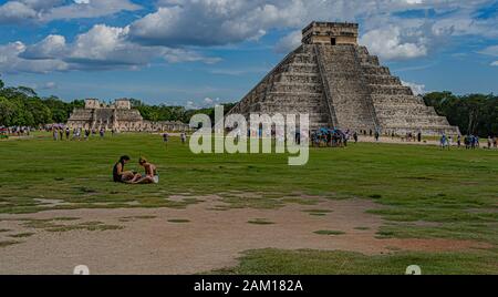Tourists relaxing on the lawn by the massive step pyramid, known as El Castillo or Temple of Kukulcan. Stock Photo