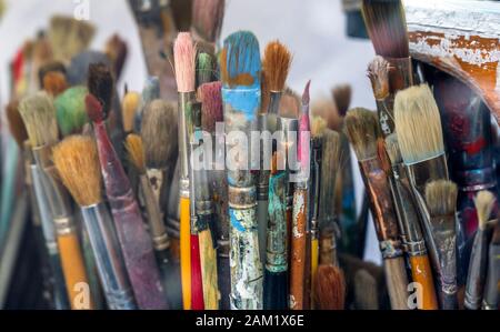 Various art brushes of different thicknesses and shapes for working with oil or acrylic paint stand in the artist’s workshop waiting for the creation Stock Photo