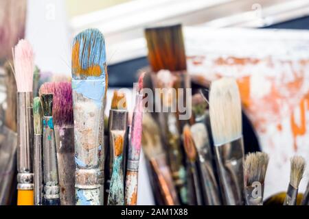 Various art brushes of different thicknesses and shapes for working with oil or acrylic paint stand in the artist’s workshop waiting for the creation Stock Photo