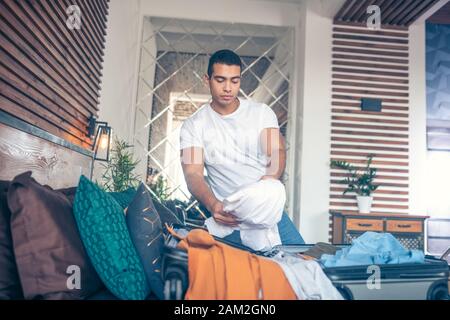 Dark-haired young man in white tshirt getting ready for trip Stock Photo