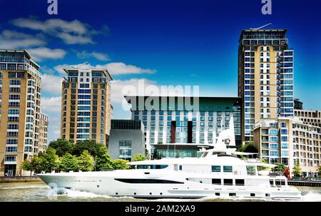 Luxury Yacht on River Thames London sailing in front of modern apartment buildings on riverbank Stock Photo