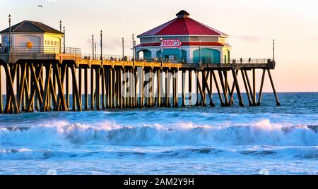 Famous Huntington Beach Pier at Sunset. Huntington Beach is a worldwide tourist destination and is known as Surf City USA. Stock Photo