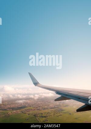 aiplane window view with ariplane wing, landscape and blue sky copy space Stock Photo