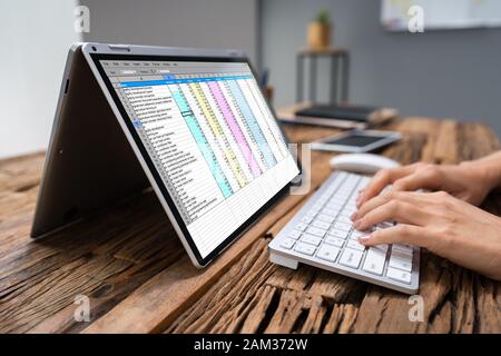 Close-up Of A Businesswoman's Hand Examining Spreadsheet On Laptop In Office Stock Photo