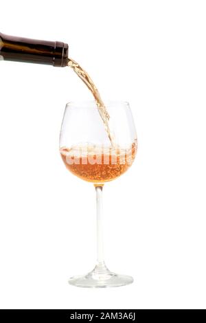 pouring orange wine from a dark brown bottle into a round glass on a tall stalk Stock Photo