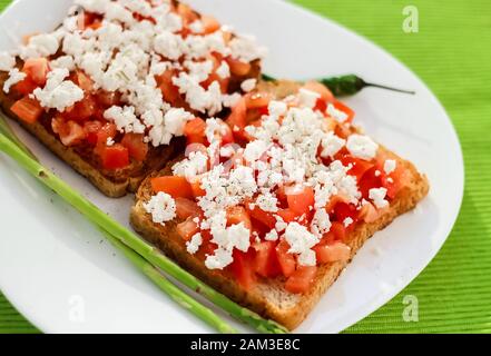 Two Sandwiches with feta, tomatoes, oregano and olive oil. Traditional Greek snack Stock Photo