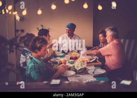 Happy and friendly people having dinner together at home or restaurant in friendship - family with different ages and generations men and women enjoyi Stock Photo