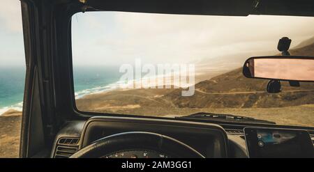 Inside view of car with mobile modern phone gps system to find the road and use maps in off road scenic place with beach and mountains view - concept Stock Photo