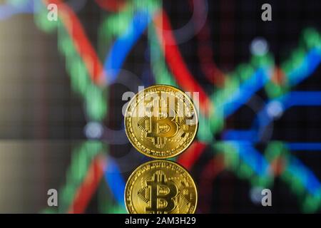 Bitcoins and virtual money concept. Gold bitcoins with chart of growing and falling valuance of a cryptocurrency. Mining or blockchain technology Stock Photo