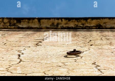 Close up old iron ring on the old yellow wall background and blue sky. Stock Photo