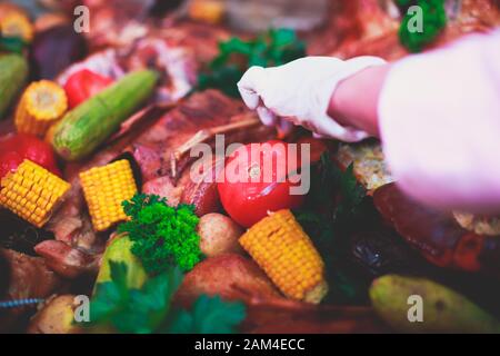 Big giant dish plate with roasted full pig pork head, served in restaurant with variety of vegetables and different meat assortment - lamb, ham and ch Stock Photo