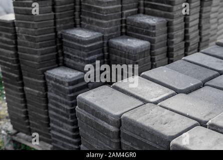 Stack of paving stone on construction site. Bricks for paving stones stacked in stacks, background texture structure. Gray pavement bricks for Stock Photo