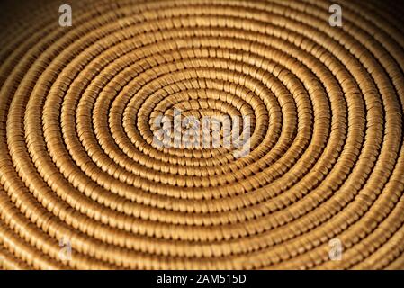 Background of a spiral woven wicker texture - Detail of a brown and orange basket, selective focus Stock Photo