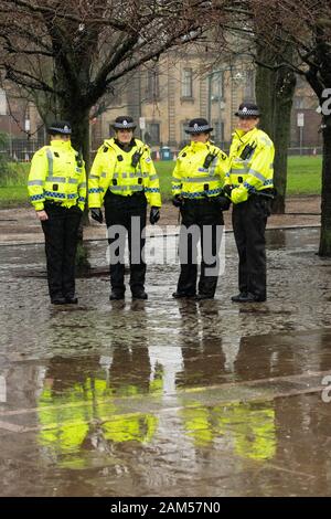 Glasgow, Scotland, UK. 11th Jan, 2020. One of several groups of police officers standing in the pouring rain at the entrance to Glasgow Green as thousands of independence supporters march through the streets of Glasgow. The event has been organised by All Under One Banner, the grassroots pressure group for Scottish Independence Credit: Kay Roxby/Alamy Live News Stock Photo