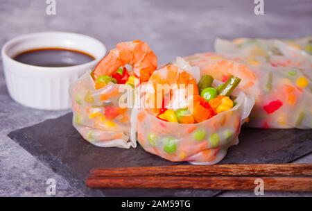 Spring rolls with vegetables and shrimps in a rice paper on the black plate. Stock Photo