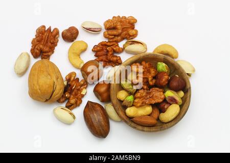 Selection of walnuts, hazelnuts, cashew nuts and almonds in miniature bamboo bowl on white surface with copy space Stock Photo