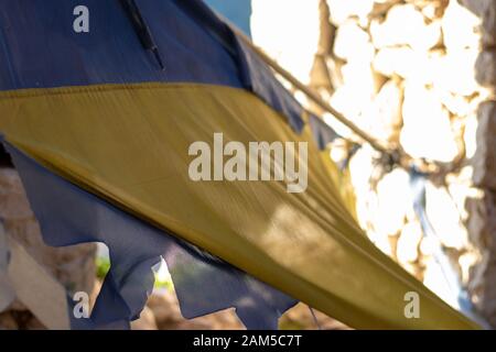 Torn closeup of an ukranian flag, destroyed , ruined , cut. Symbol of conflict and war in ukraine Stock Photo