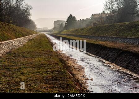 Gabrovacka River - Gabrovacka reka channel on the outskirts of the City of Nis in Serbia, with low water level on the autumn foggy day. Stock Photo