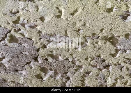 Painted cracked and peeling render coming away from cement background surface. Old paint texture, rough texture, peeling paint, poor condition. Stock Photo