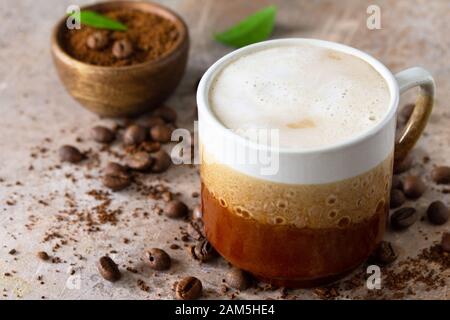 Morning coffee concept. Cup of coffee latte, coffee beans and ground powder on a stone old concrete countertop. Stock Photo