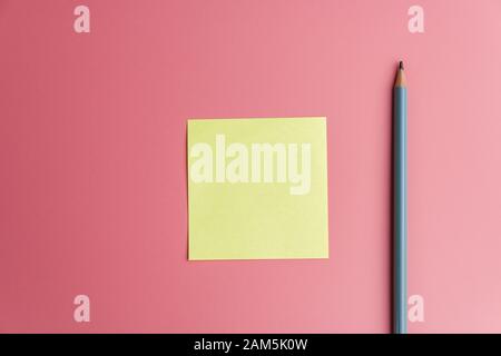 one yellow sticky note reminder and a pencil on a red background Stock Photo