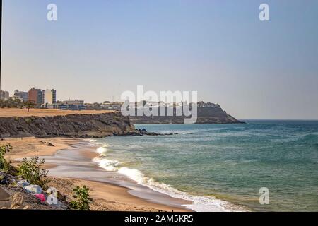 Views of the coastline of Dakar, Senegal, Africa. It is a beautiful long beach and in the background you can see buildings and palm trees and a Stock Photo