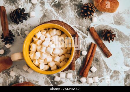 a cup of Christmas New Year delicious hot chocolate and cocoa with marshmallows sprinkled with cocoa powder, cones and croissants, cinnamon on a gray Stock Photo