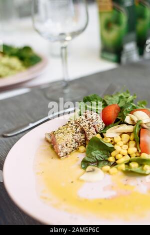 Salad of greens, canned corn and fried tuna in sesame seeds. Recipe for an expensive fish. Stock Photo