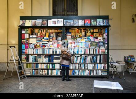 A woman from back choosing a book at the second-hand book market under the arcades of Via Po in the historic centre of Turin, Piedmont, Italy Stock Photo