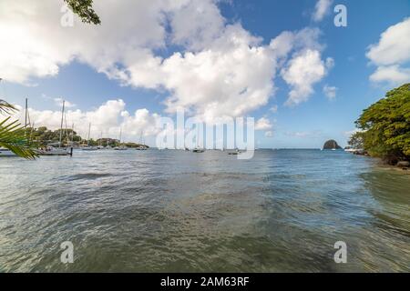 Sailboats on mooring in Blue Lagoon with fort Duvernette on background, Saint Vincent, Saint Vincent and the Grenadines Stock Photo