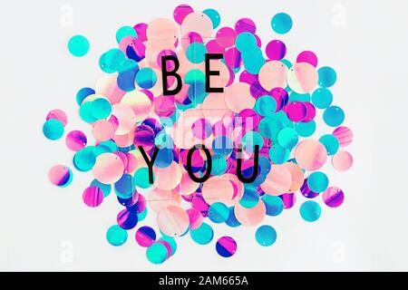 Background with shiny pink, purple and holographic sequins with words Be you, abstract background. Stock Photo