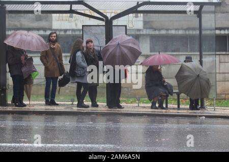 COIMBRA, PORTUGAL - 04 January 2016 - People try and keep dry during heavy rain in the Praca da Republica in central Coimbra Portugal Stock Photo