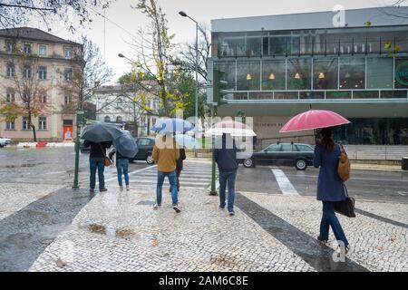 COIMBRA, PORTUGAL - 04 January 2016 - People try and keep dry during heavy rain in the Praca da Republica in central Coimbra Portugal Stock Photo